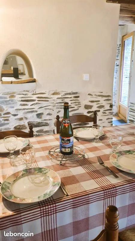 Coin repas du gîte avec table dressée devant un mur en pierre
